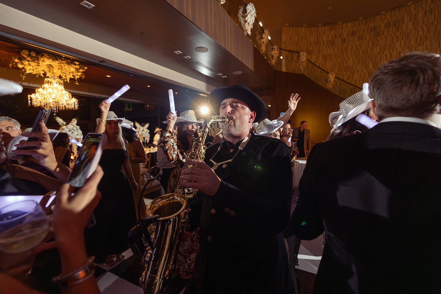 DJ vs band hybrid in action: Matt Thelen playing live saxophone surrounded by cheering wedding guests with glow sticks at a luxury Dallas reception