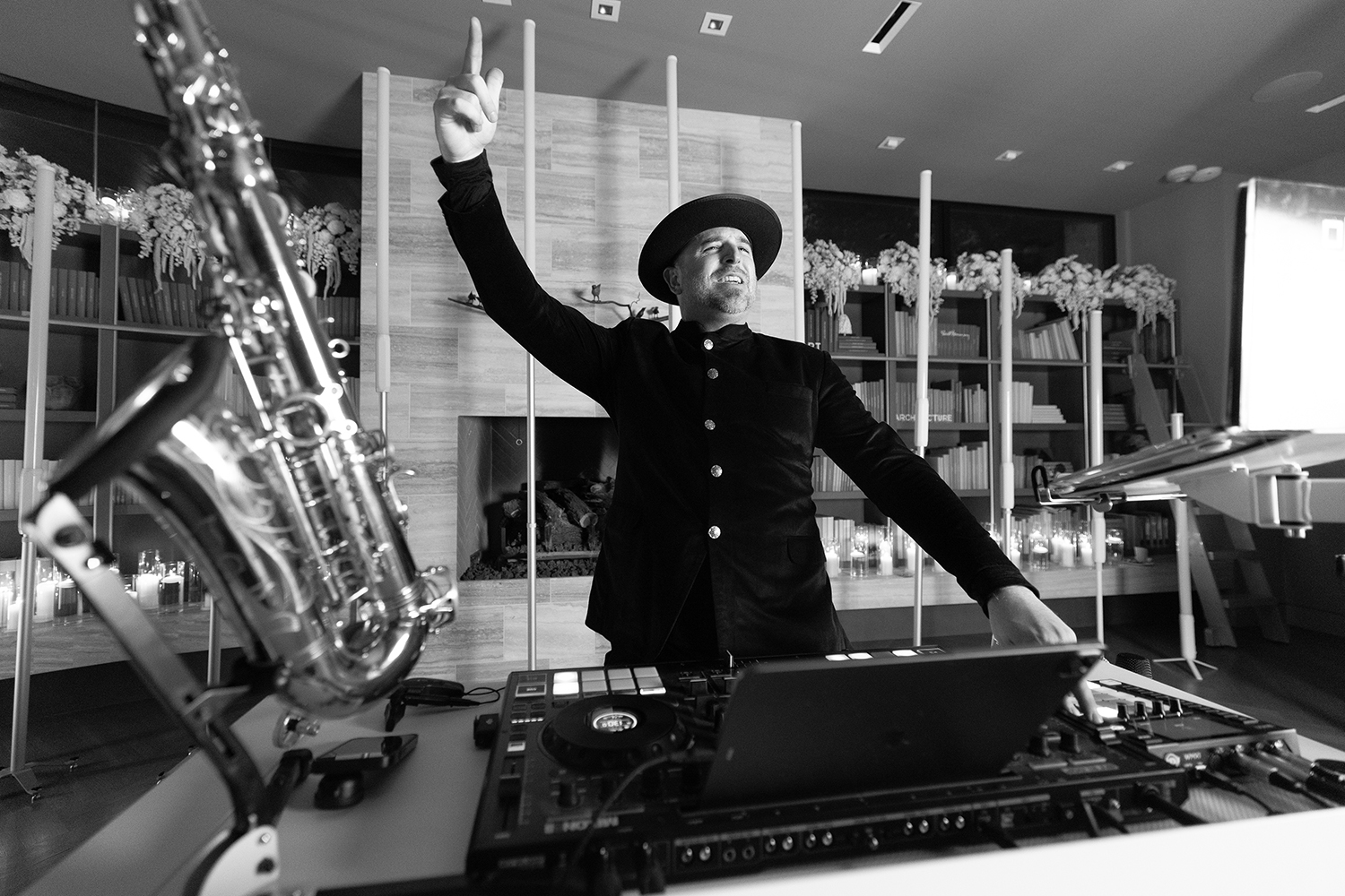 DJ vs band hybrid setup at a Dallas wedding reception: DJ booth, laptop, and controller next to a live saxophone on its stand, with Matt Thelen mid-performance